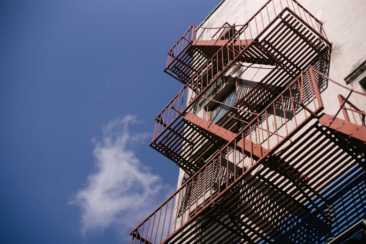 Außen liegende Stahltreppe an einer Gebäudewand vor blauem Himmel